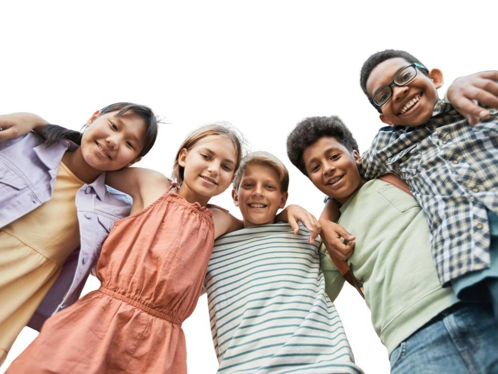 Group of 5 preteen aged kids with their arms over each other's shoulders smiling