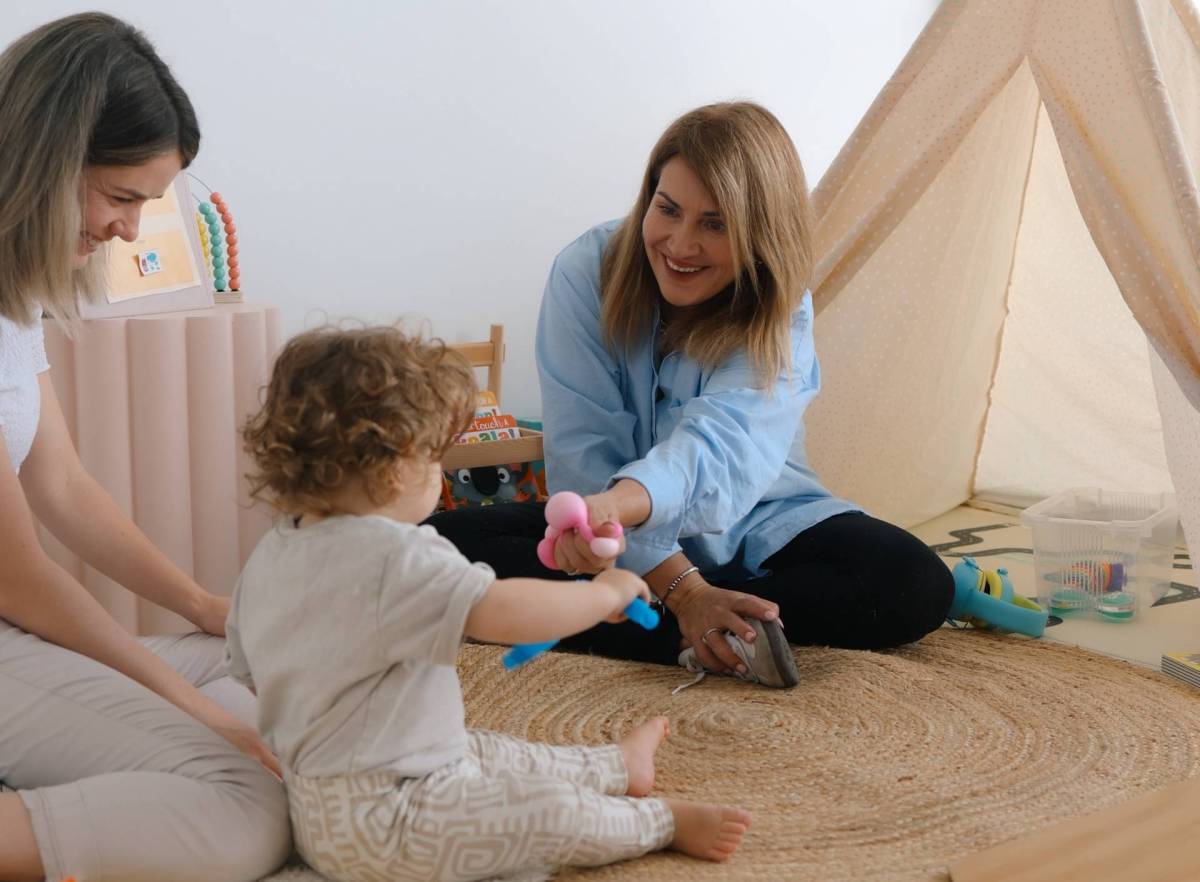Therapists with baby sitting on a rug with a toy