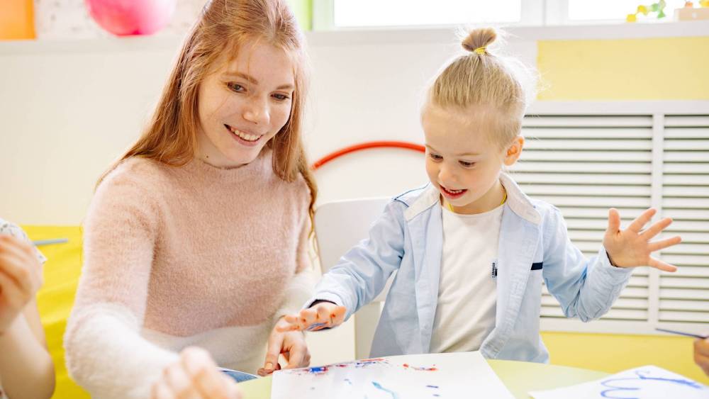 Child doing finger painting with a woman