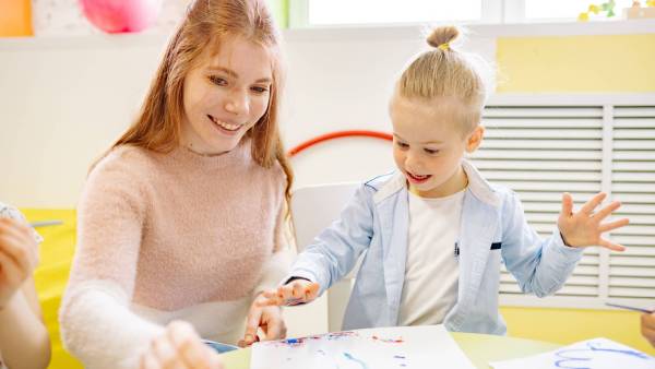 Child doing finger painting with a woman