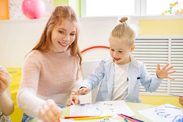 Child doing finger painting with a woman